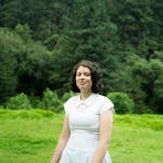 Woman in a white dress stands in a lush forest setting in Amecameca, Mexico.